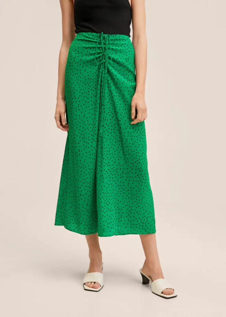 green flowing bias cut midi skirt with black polka dot print and ruching detail at the waist with spaghetti straps to tie in a bow over the tummy. 