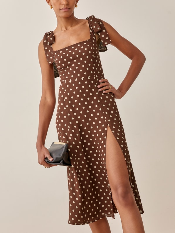 The brown and white polka dot Twilight dress from reformation is fitted in the bodice with a relaxed fitting skirt with a slit, so you get structure and comfort all in one. This dress features cute tie straps, a smocked back bodice to provide a little bit of stretch. 