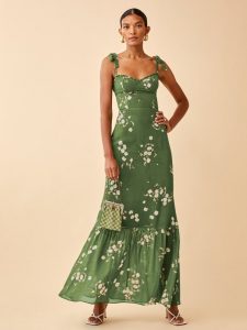 The Jasen is a full length dress that's fitted in the bodice and waist with a relaxed fitting trumpet skirt. It has ruffle detailing and tie straps. Mossy Green base with delicate white florals. 