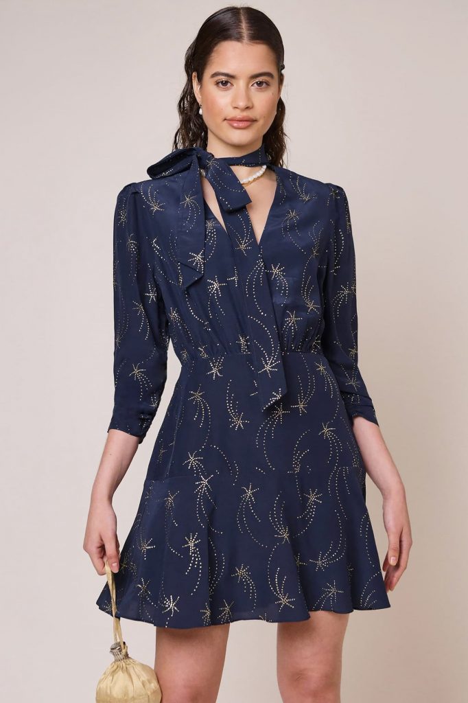 Midnight blue long sleeved mini dress with pussy bow tie neck detail and glitter star print in gold. 