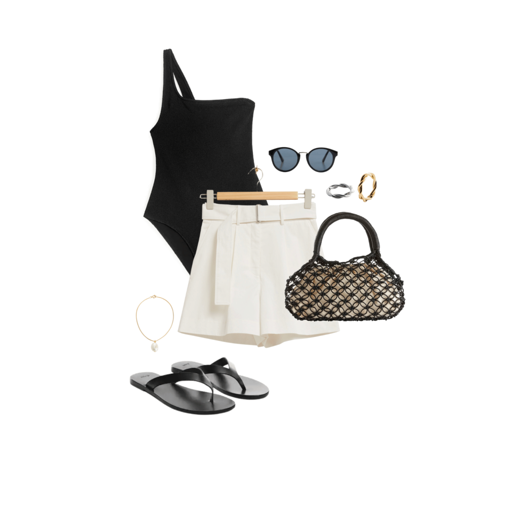 summer outfit consisting of black swimsuit, white cotton shorts, gold pendant necklace, chunky ring, raffia bag, gold anklet, and black sandals. 