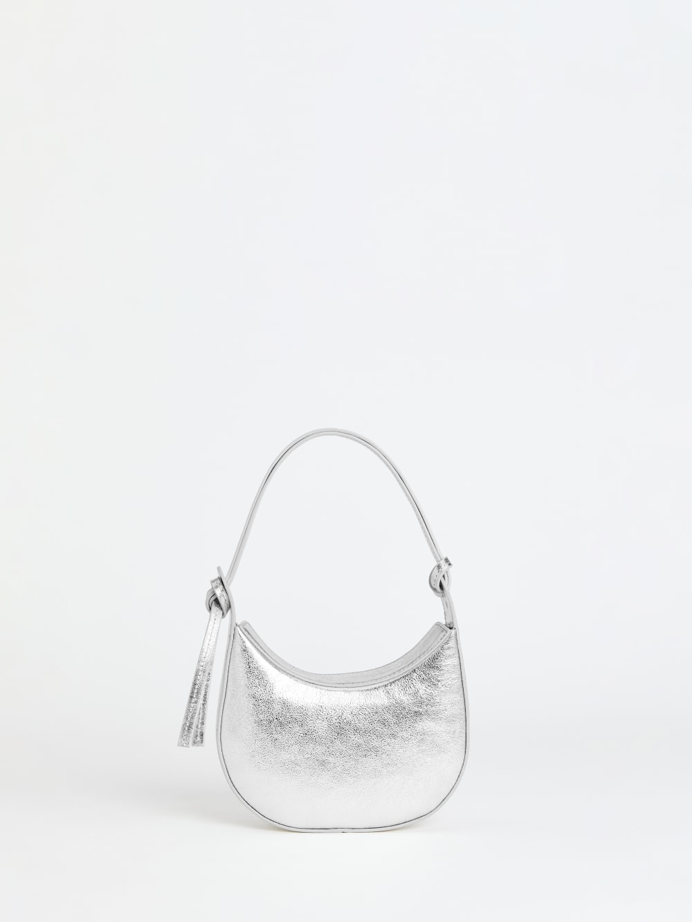 Reformation silver Crescent shaped leather shoulder bag with a decorative tie detail, magnetic closure, and interior pockets.