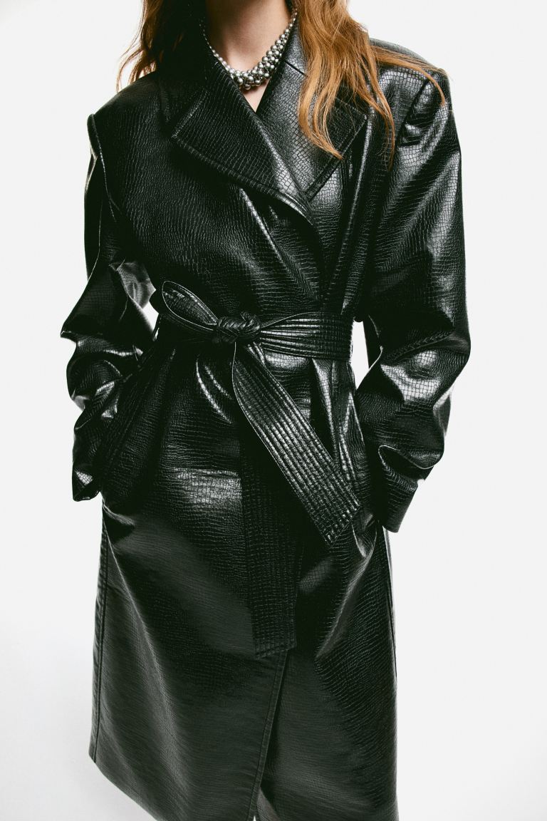 H&M black coated trench coat with textured vinyl finish has an oversized fit and a self-tie belt. 