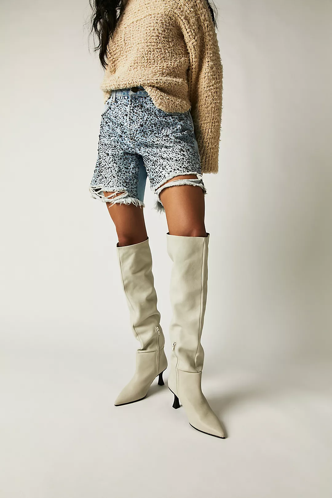 Modernly chic, these Free People tall cream leather boots are featured in a slouchy style and minimalist design with a skinny flared heel for slight boost.