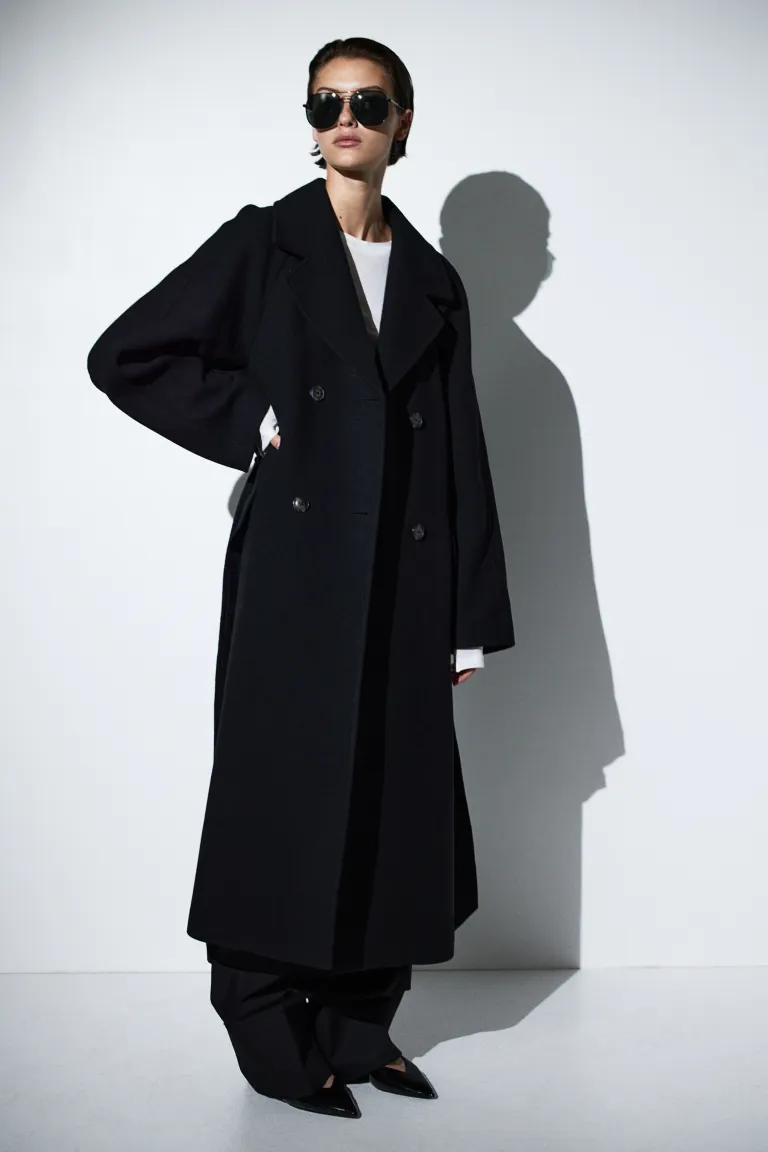 H&M black Calf-length, double-breasted coat in woven fabric containing some wool. Notch lapels, buttons at the front and a wide, detachable tie belt at the waist. Long raglan sleeves, diagonal front pockets with a flap, and a single back vent. Lined.