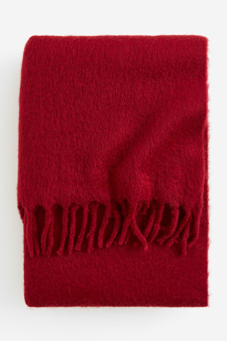 Chic Secret Santa Gift Ideas for every budget in 2023. H&M Soft red blanket containing some wool with fringes along the short sides.